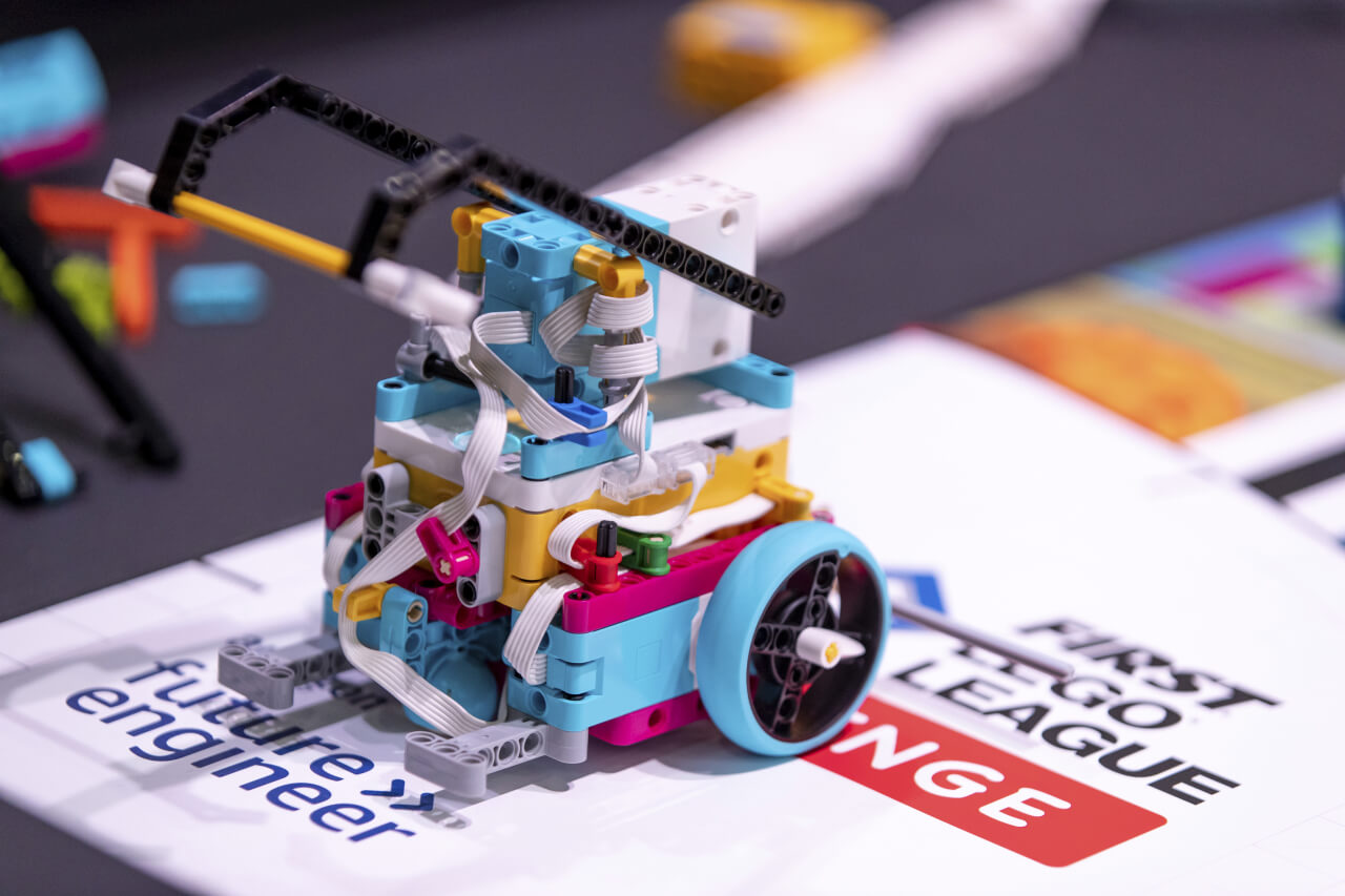 רובוט עם זרועות, בנוי מחלקי LEGO, נוסע על זירת התחרות